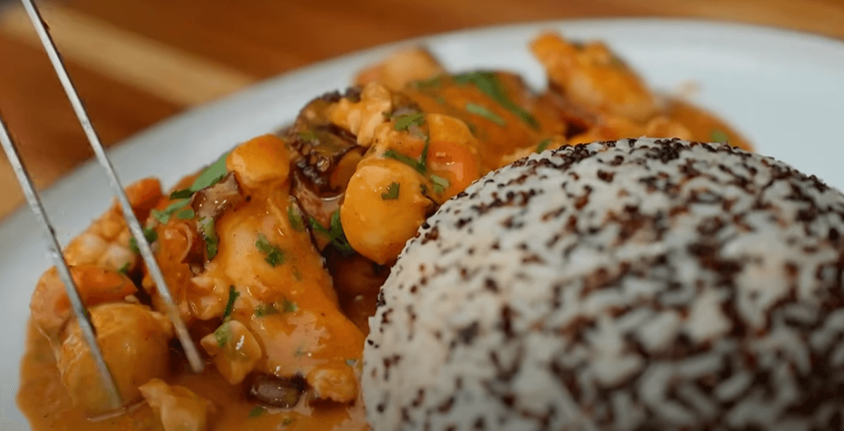 Plato de Pollo a lo Macho servido sobre una cama de arroz con quinoa negra.
